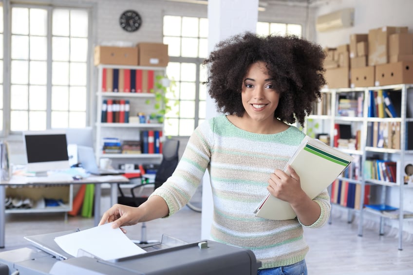 Smiling assistant using copy machine at work